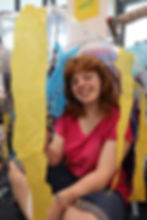 Student smiles to camera whilst sitting in a colourful jellyfish made out of an umbrella