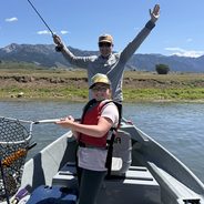 Western River Anglers anglers celebrating a day of fly fishing on a Wyoming river with mountain views.