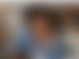 Woman sitting at a table looking stressed while checking her phone with laptop and papers nearby