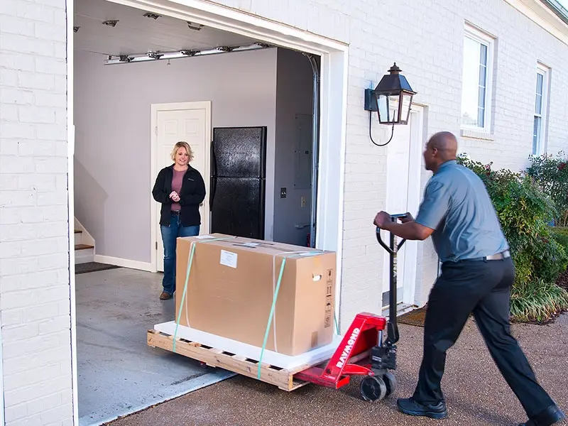 Eye-level view of a delivery driver moving a pallet jack through a wide open business dock door