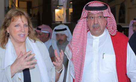 Dr Lisa Urkevich and a Saudi dignitary talking and walking with a group of men following them
