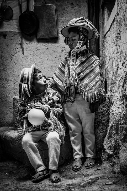 Two young brothers in traditional Andean clothing in their family kitchen, Sacred Valley, Peru