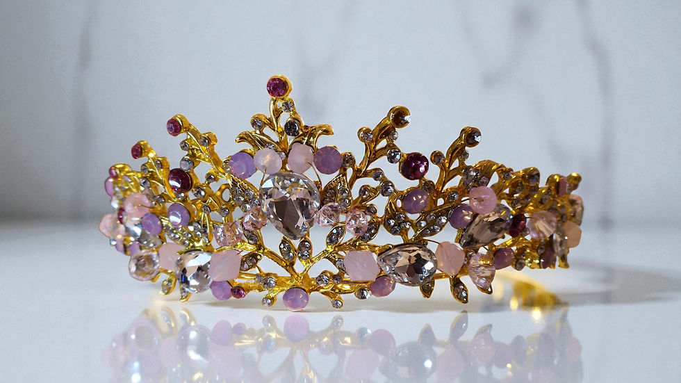 Elevate any special occasion with The Claire Bianca, a gold tone tiara with pink, lilac, and clear rhinestones in a floral de