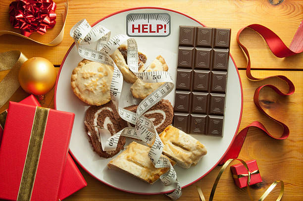 Plate with bathroom scales displaying the word help alongside Christmas foods and decorations.