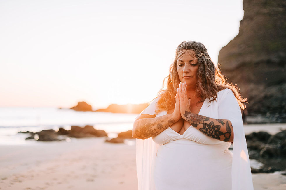 Woman in white dress meditating at the beach.