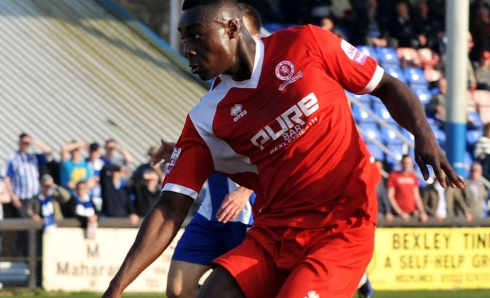 Tobi Sho-Silva playing for Welling United in a red football outfit during a match