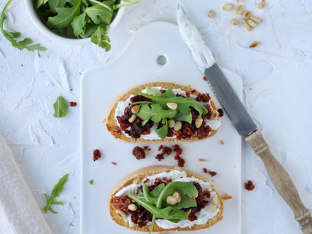 Bruschetta met ricotta, zongedroogde tomaten, rucola en pijnboompitten