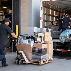 Warehouse worker loading liquidation pallets onto a truck for scheduled auction pickup