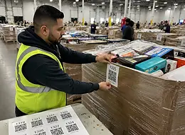Warehouse worker attaching GavelTags⢠QR scan-to-bid labels to liquidation auction lots inventory