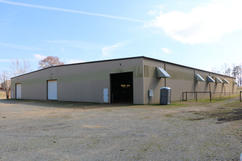 Custom built horse arena with overhead doors, ventilation fans, interior stalls and overhead lighting
