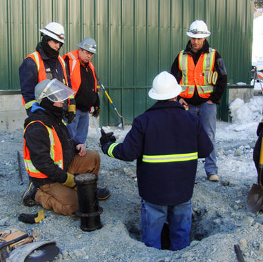 group of construction workers gathered around their supervisor who is discussing a hazard on-site.