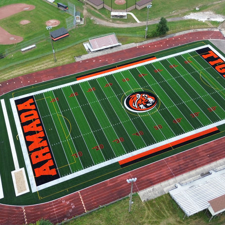 A football field featuring an orange and black logo prominently displayed at the center.