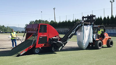 A man loads equipment onto a field as part of the synthetic turf removal process.
