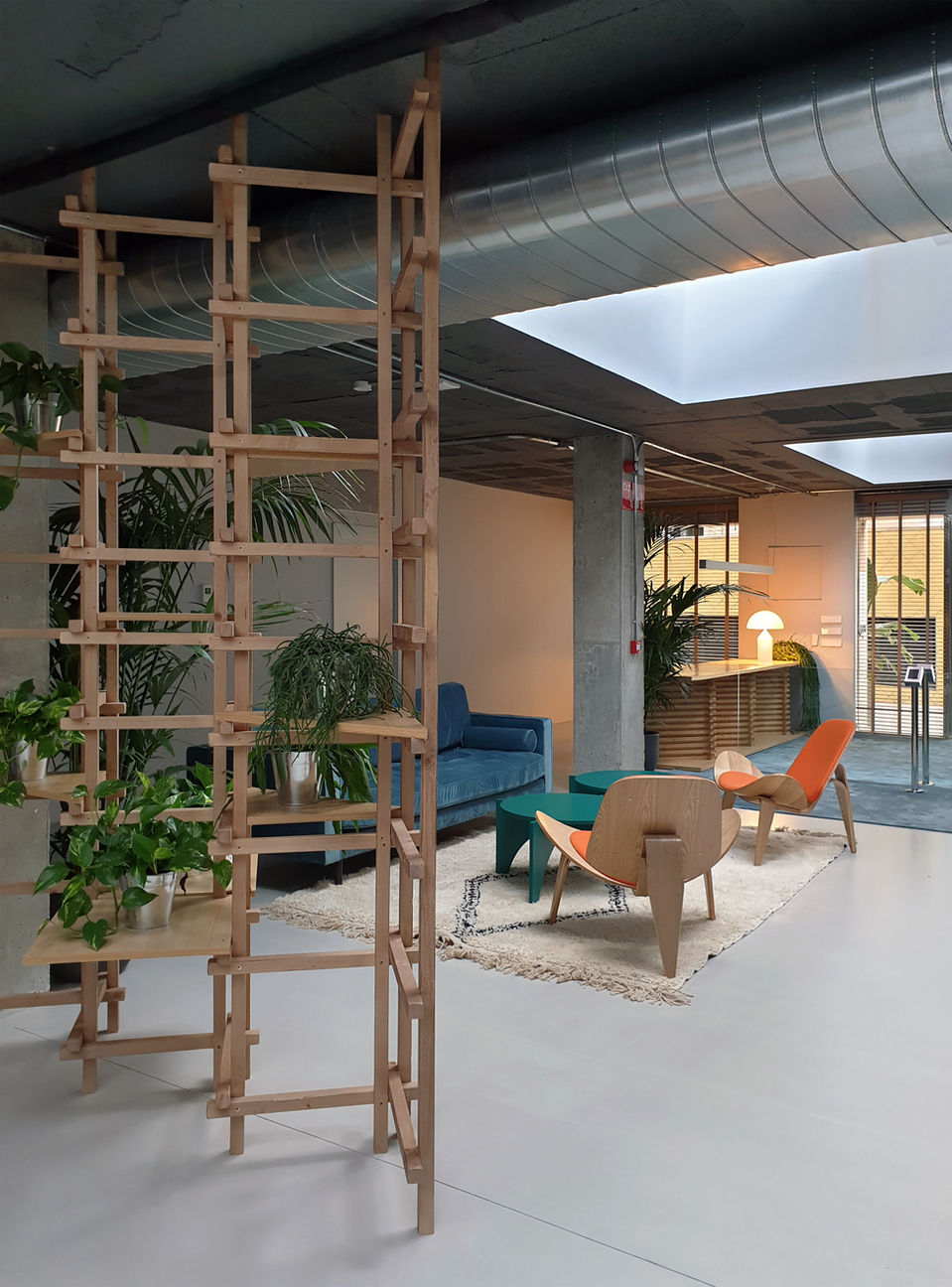 Espacio de co-working moderno y funcional diseñado para fomentar la colaboración. La madera clara escandinava (estilo Nordic) domina el ambiente, aportando luminosidad y calidez. Toques de color vibrante en mobiliario y accesorios inyectan energía y personalidad al espacio de trabajo compartido.