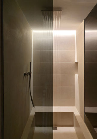 Ducha moderna con mampara de cristal y luz LED vertical. Ambiente de baño oscuro y minimalista.