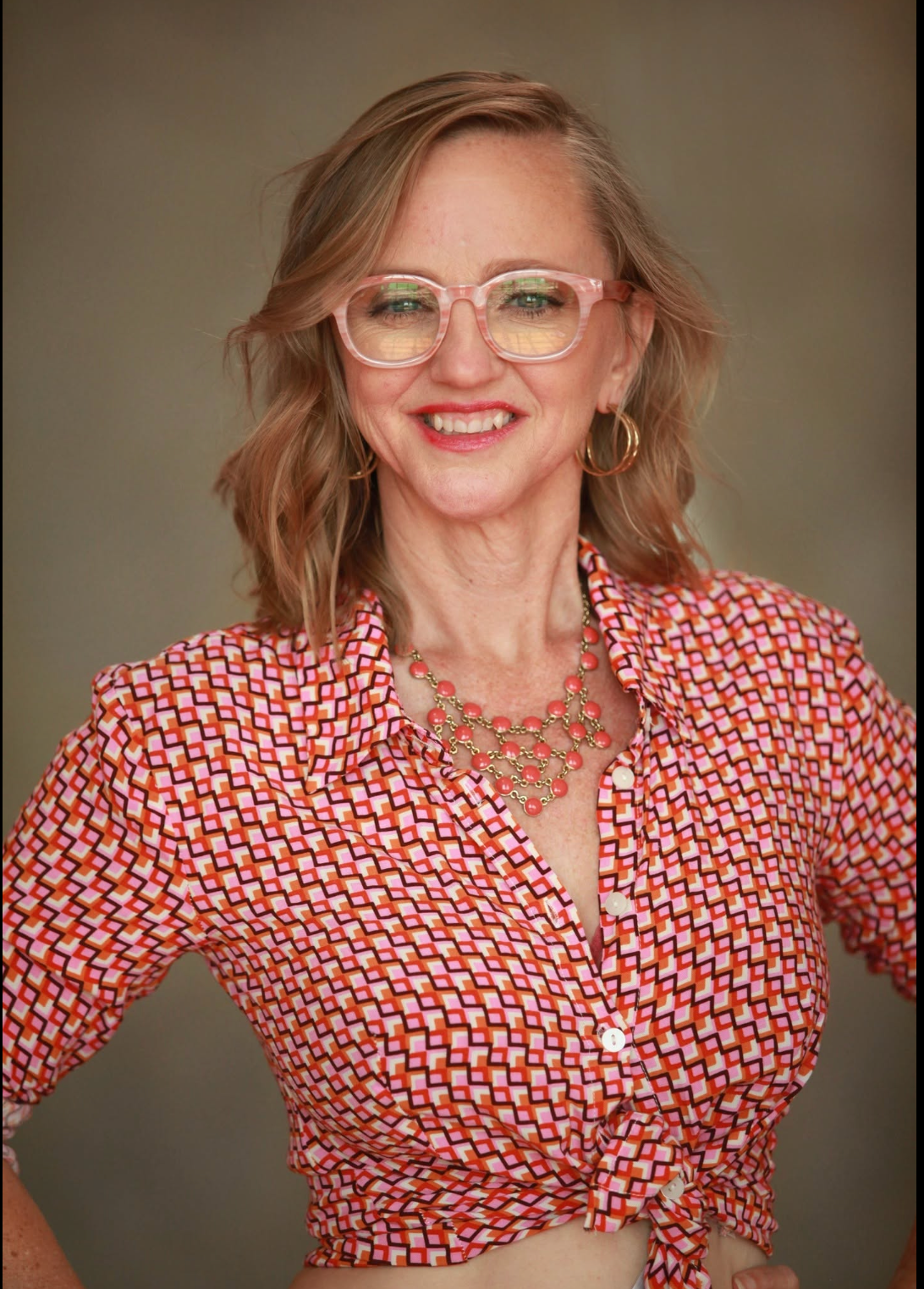 Lindsay A. Miller smiling in pink glasses and a patterned shirt