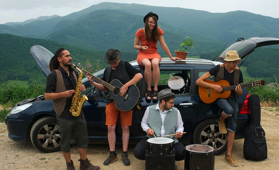 Photo des membres du groupe Physalis en Ariège, dos aux montagnes avec leurs instruments de musique.