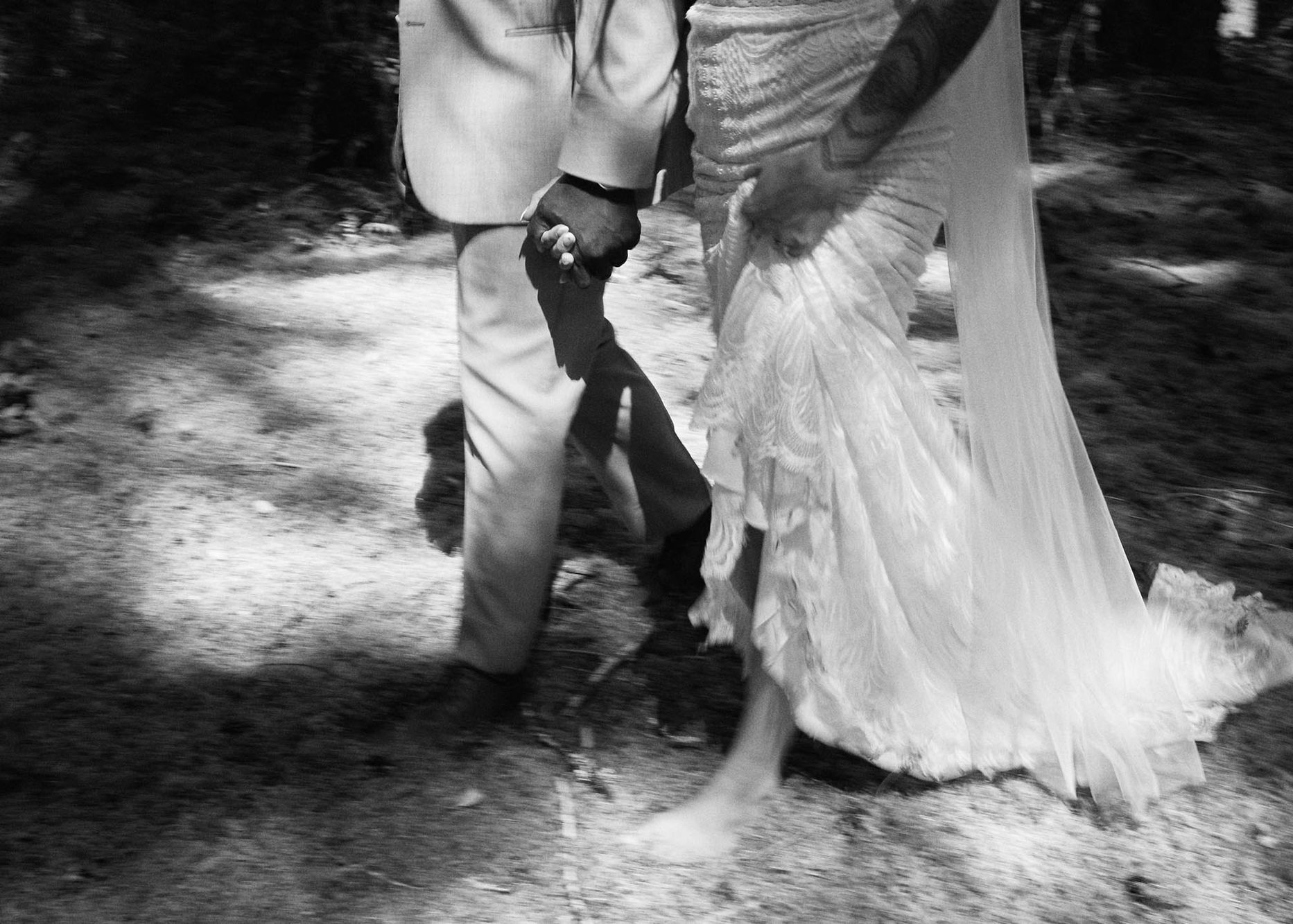 Bride and groom walking along a mossy woodland trail, captured by a professional Vancouver Island wedding photographer, ideal for candid couple photos, engagement portraits, and full-day wedding photography, showcasing lush green moss, forest textures, and authentic moments in the Comox Valley.