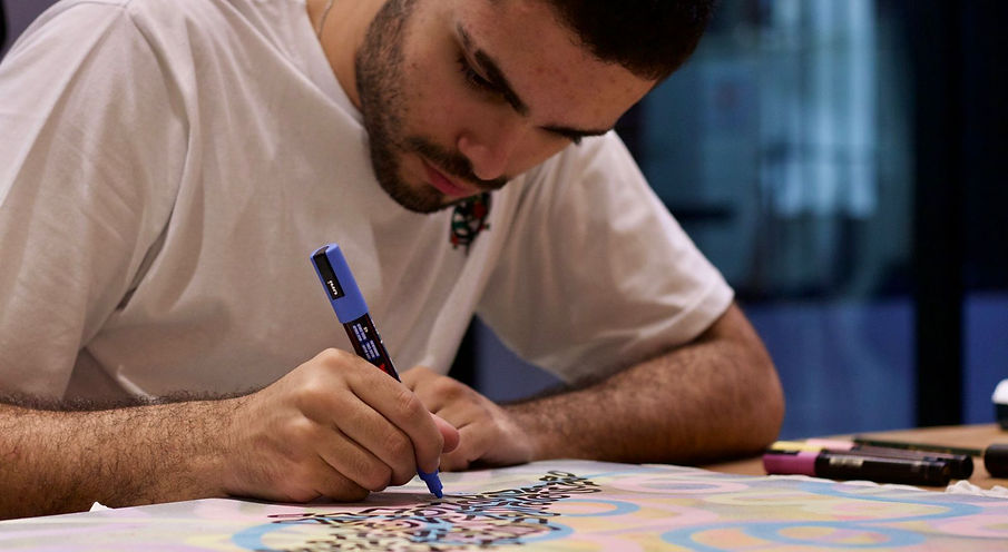 Foto do artista Fernando desenhando sobre quadro com caneta