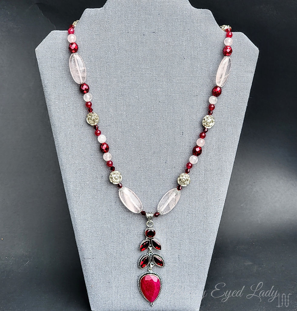 Thumbnail: necklace draped on necklace display, ruby and glass pendant below necklace of glass and rose quartz