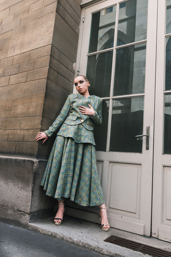 Mannequin posant près d'une porte ancienne dans un ensemble élégant à carreaux vert et doré.
