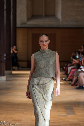Mannequin défilant de face dans une robe longue texturée vert olive sans manches, idéale pour une collection haute couture.