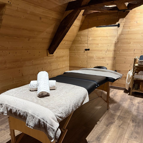 Dans une atmosphère intimiste alliant bois noble et lumière douce, notre salle de massage vous accueille avec des équipements haut de gamme : tables de massage professionnelles, linge Bouchara et Linvosges pour un confort absolu.