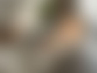 A woman wrapped in a soft blanket, eyes closed, bathed in warm sunlight—symbolizing nervous system calm and rest.