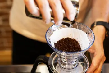 Garage T-Squareのカフェで挽いたコーヒーをドリッパーに入れている店主