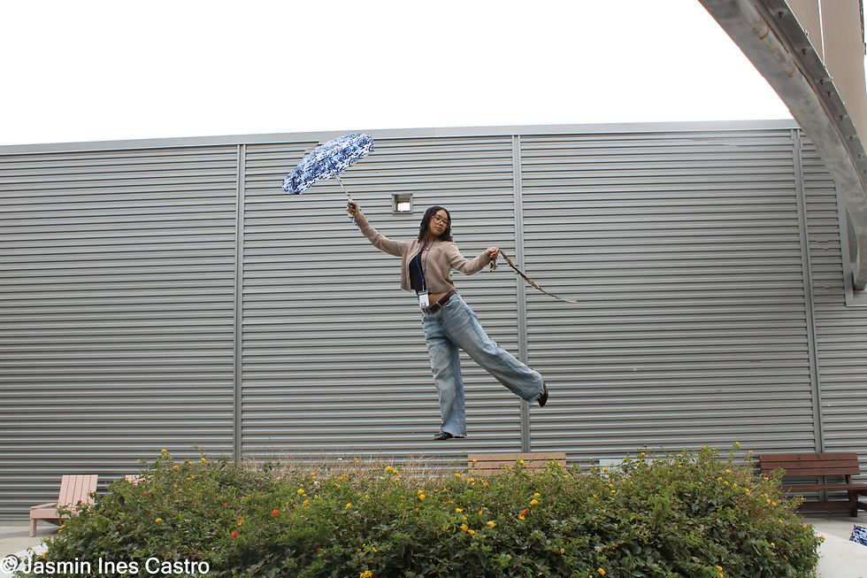 Xiomara levitating over the flowerbed with her umbrella, holding tight to her scarf
