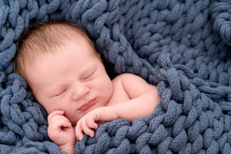 Portrait of a newborn baby boy in a blue blanket.