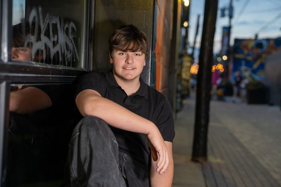 Close-up view of a young man leaning against a textured brick wall with soft side lighting