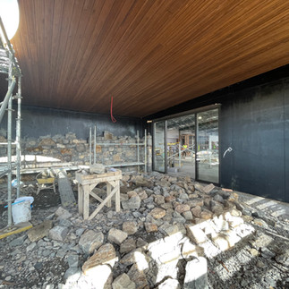 A stunning stone wall is taking shape next to the side entry doors at the front of the building.