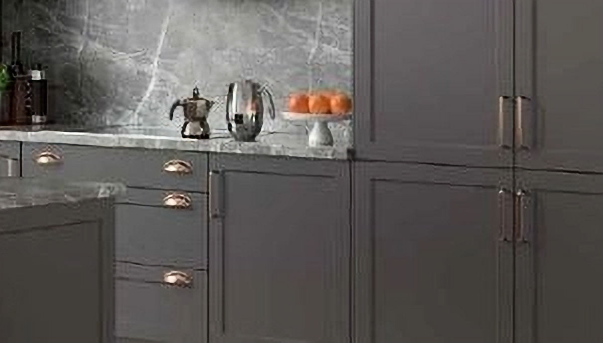 Gray kitchen cabinets with marble countertops and elegant hardware in detail.