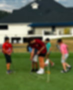 Golf coach mentoring young players on the putting green at Klubs4Kids, helping them develop skills, focus, and confidence through hands-on instruction and teamwork.