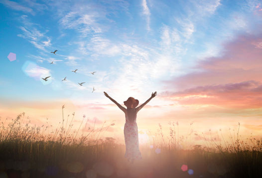 une femme lève les deux bras vers le ciel