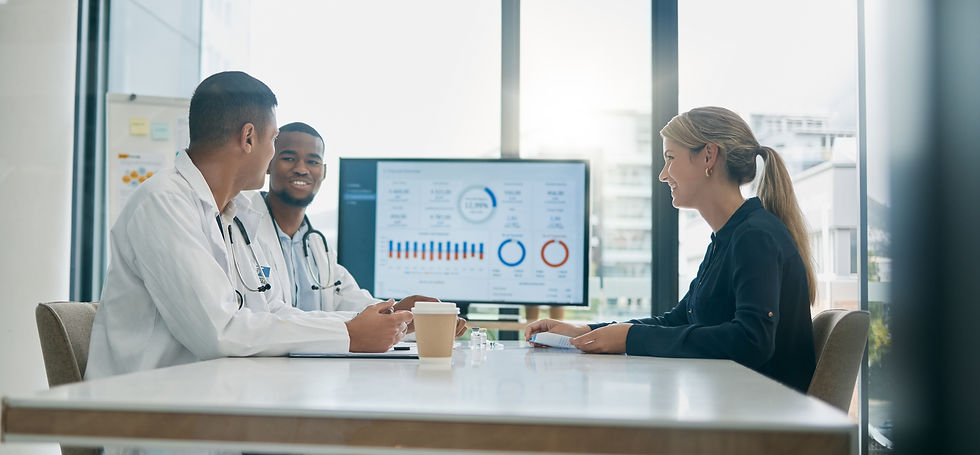 Three people sitting at a desk reviewing graphs on a computer screen.