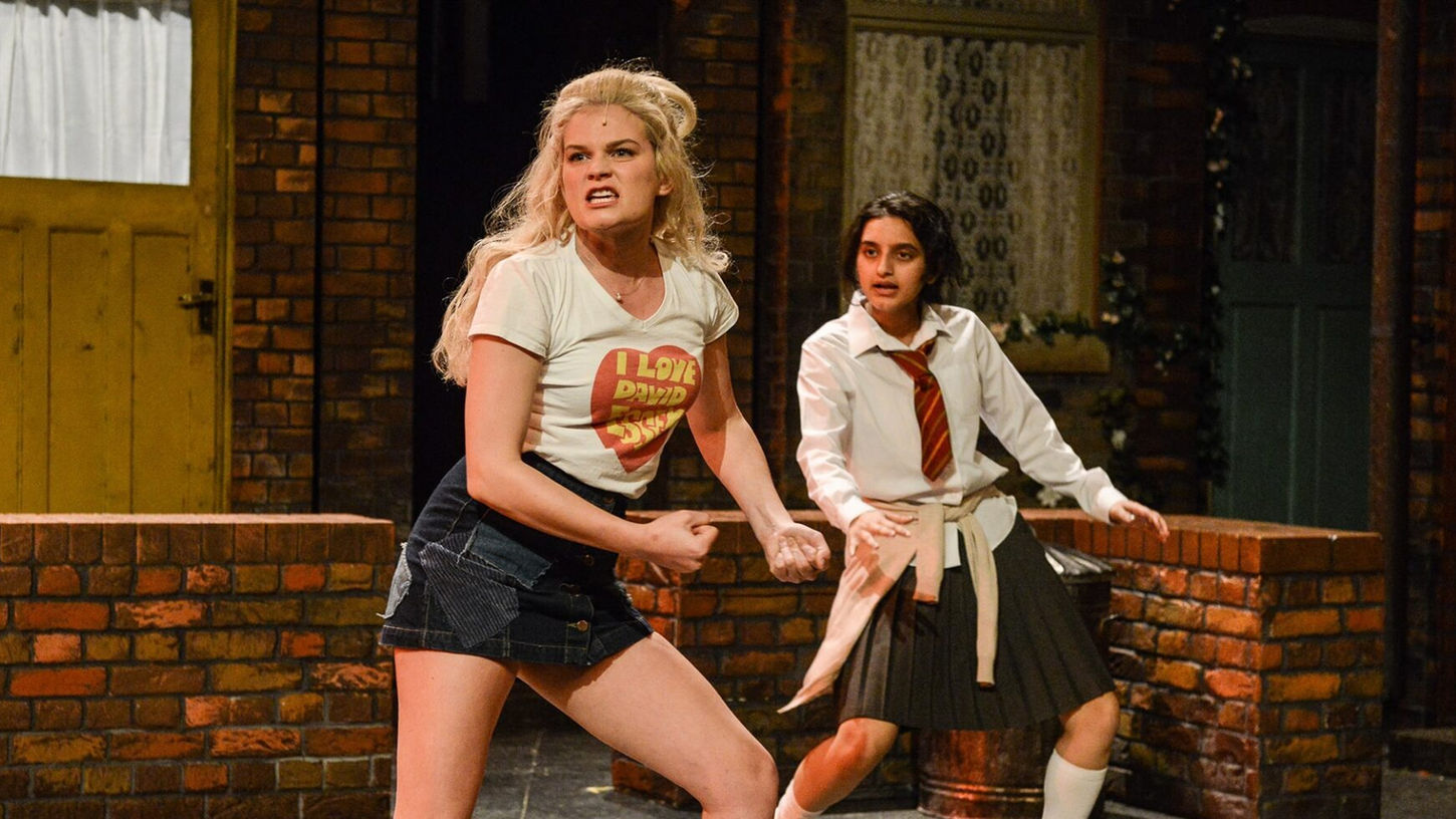 A picture of two girls in front of a brick wall