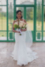 Bride posing at the venue entrance with the bouquet
