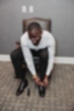 The Groom is tying his shoes while getting ready for the wedding