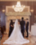Indoor wedding ceremony with bride and groom standing at altar under chandelier
