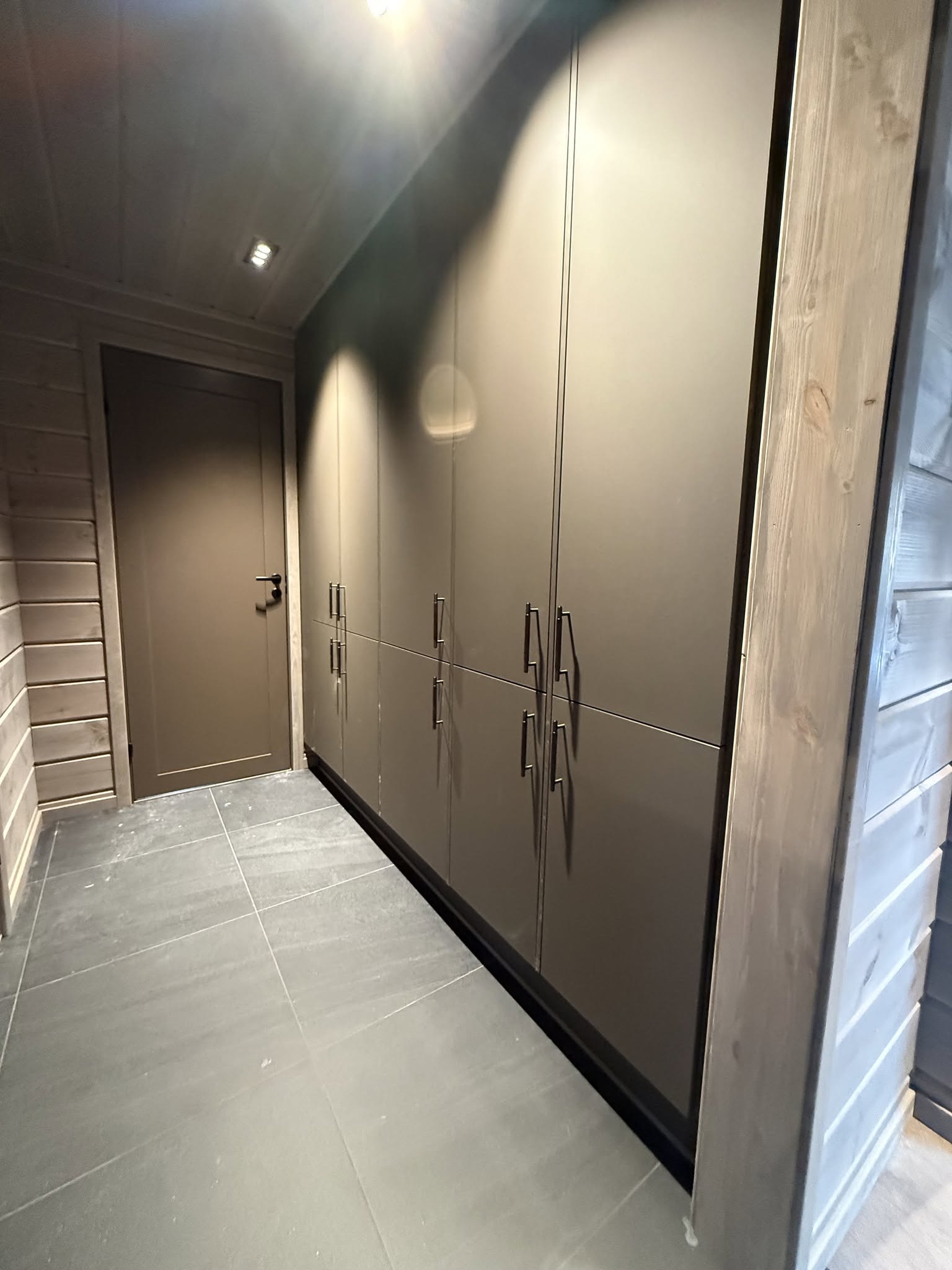 Garderobe med høye skap og innfelt belysning.