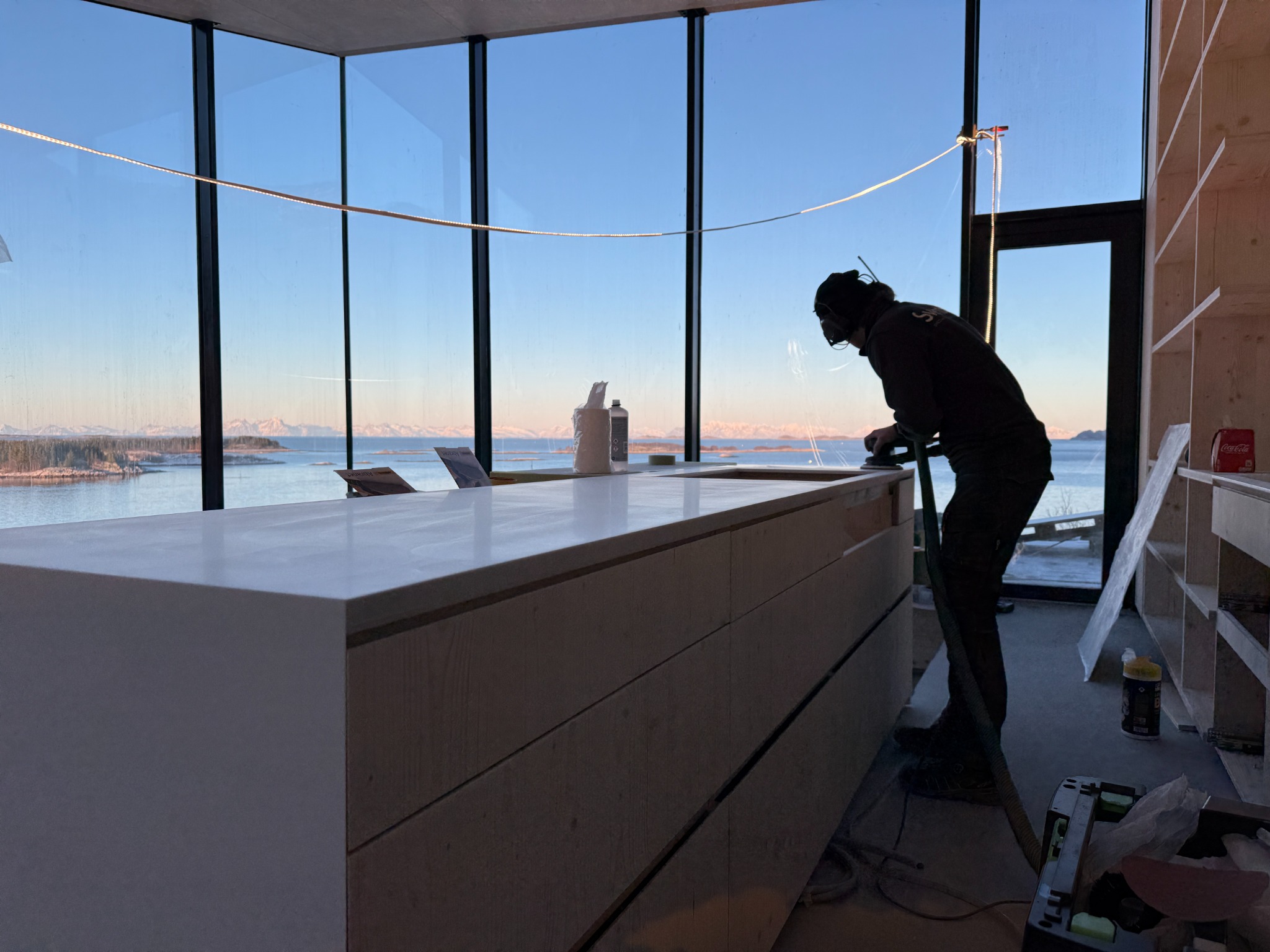 Interior installation work beside large windows overlooking the sea and mountains
