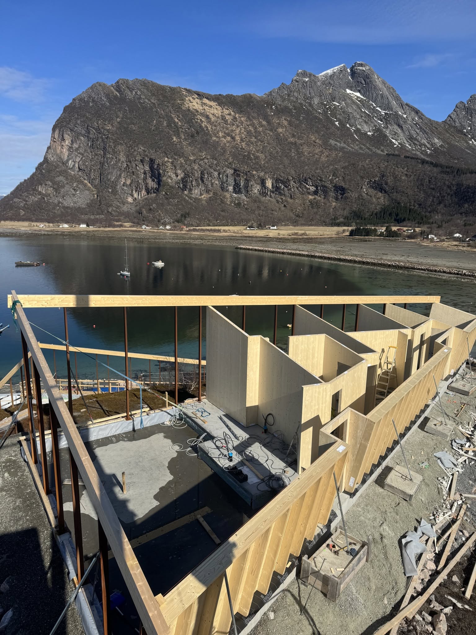 Bergtatt under oppføring, med trekonstruksjoner foran sjø og fjell
