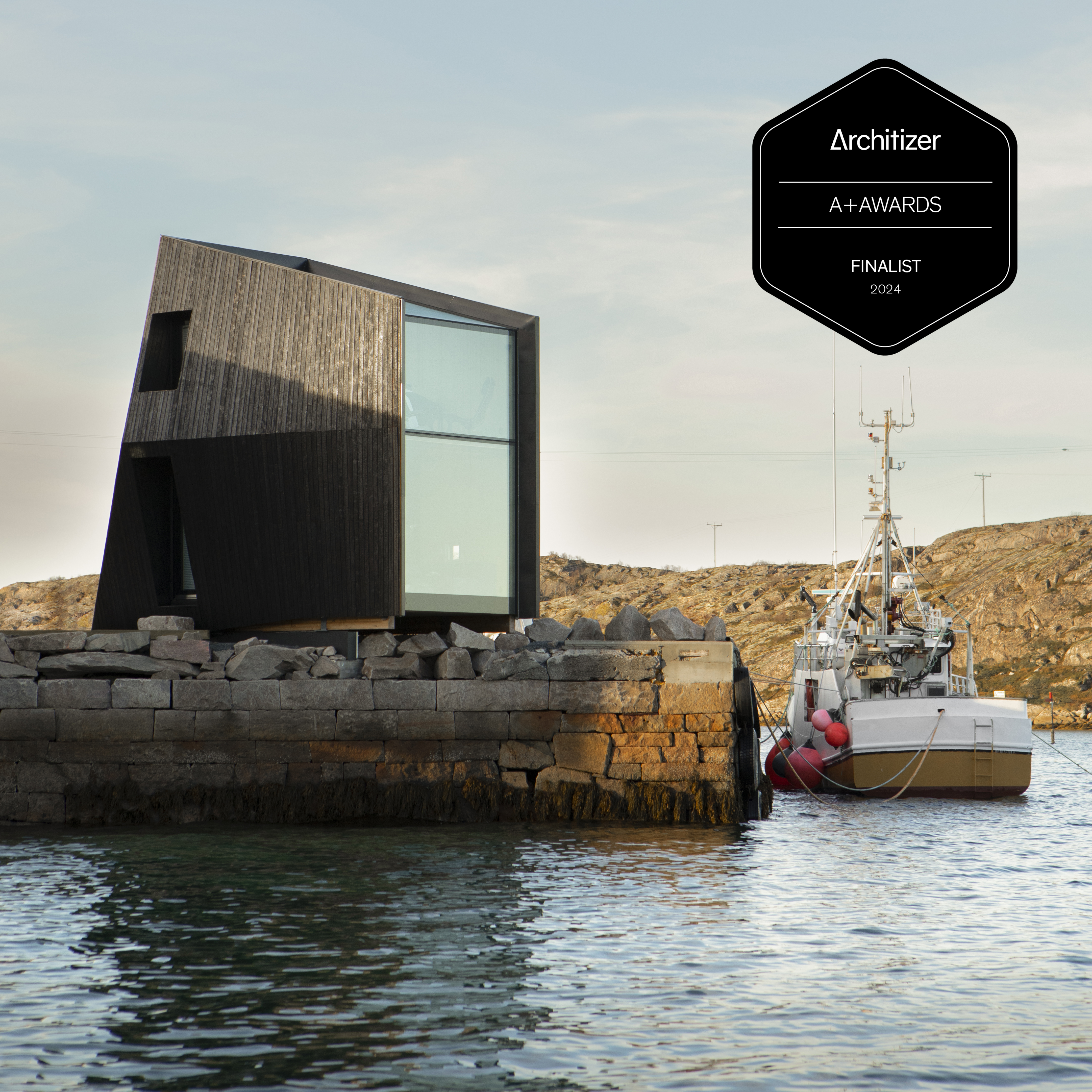 Et Manshausen-tårn på en steinkai, med merket Architizer A+Awards Finalist 2024.