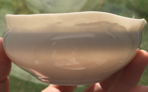 Sur cette image, on voit le translucidité de la porcelaine très fine. Le petit bol a été tourné et façonné pour lui donner des formes irrégulières