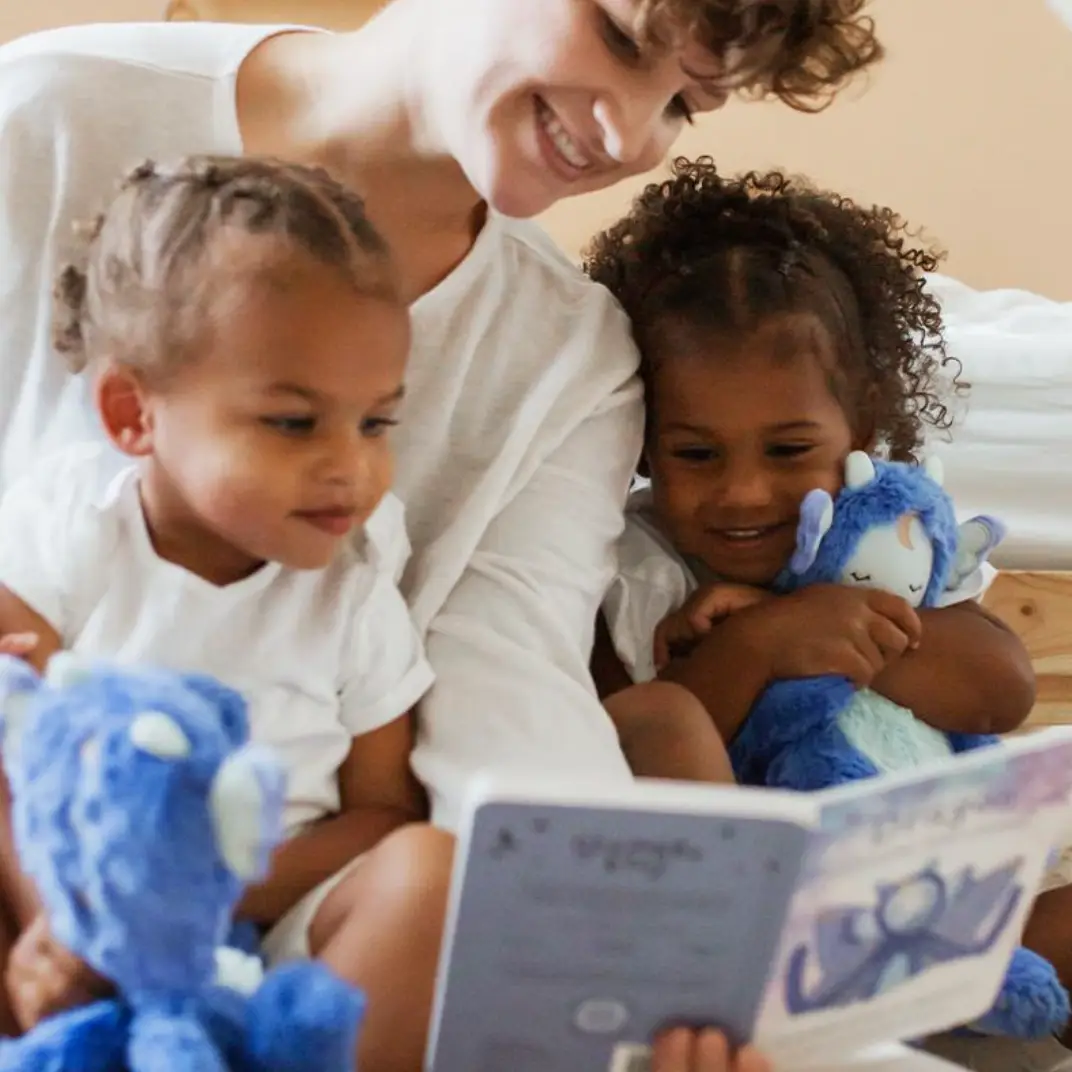 1 adult and 2 kids reading a slumberkins book