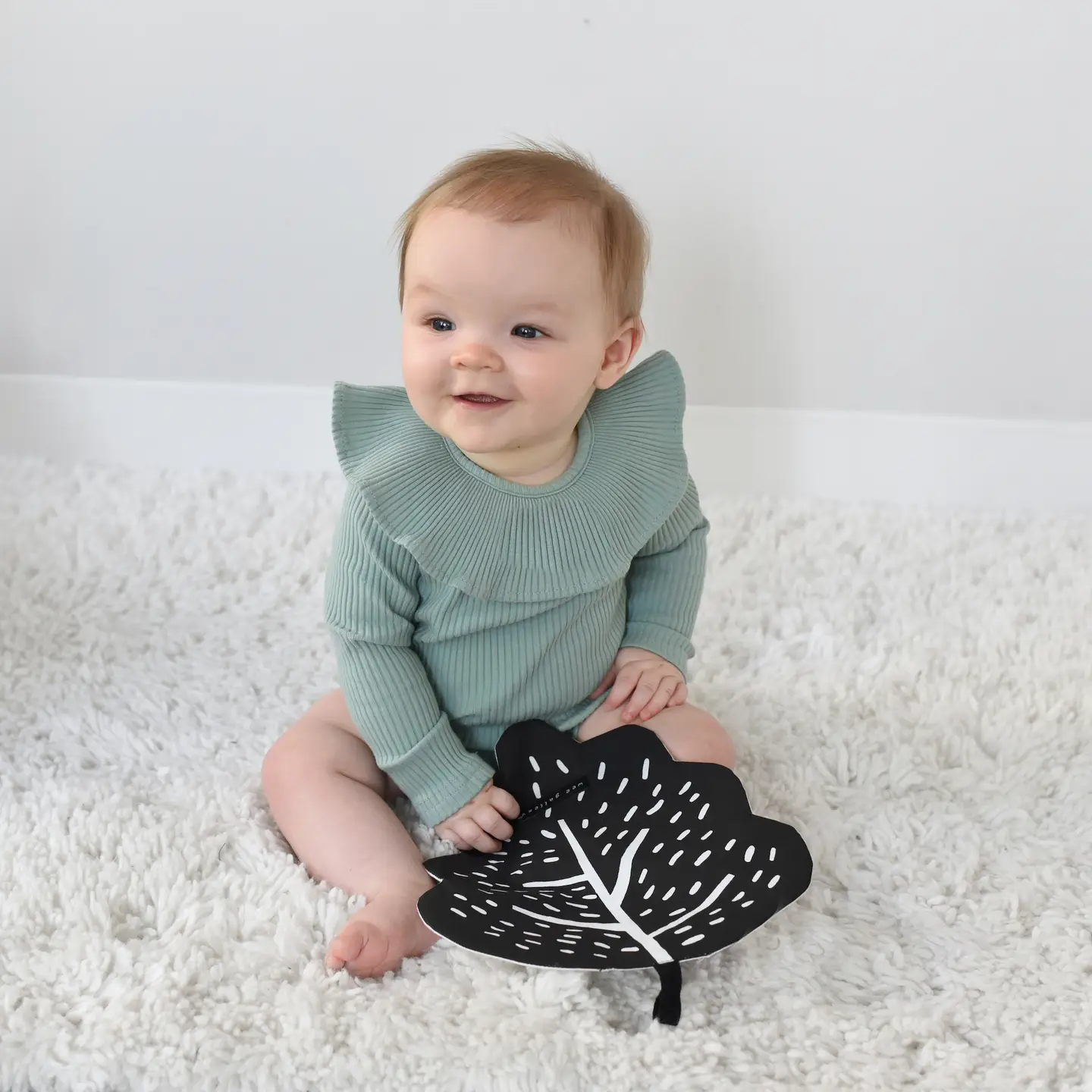 baby looking at camera while playing with crinkle leaf
