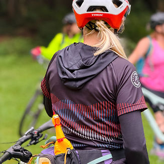 Back of a coach with blonde hair and a rubber chicken poking out of her hip pack. 