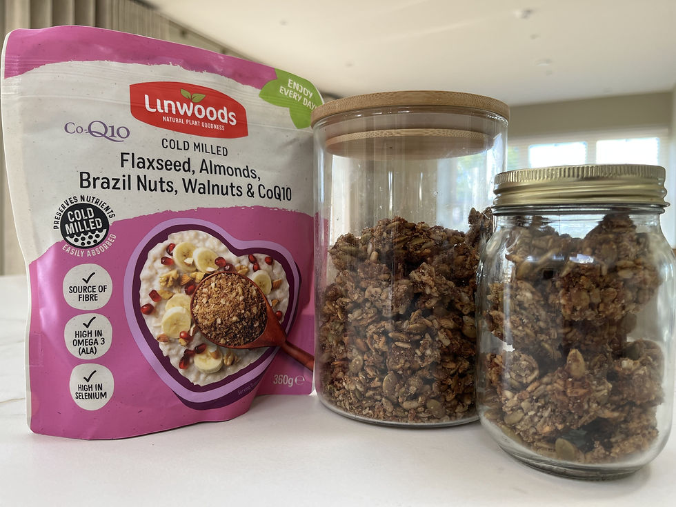 Packet of Linwoods flaxseed mix next to two glass jars filled with granola on a white countertop, soft light from windows in background.